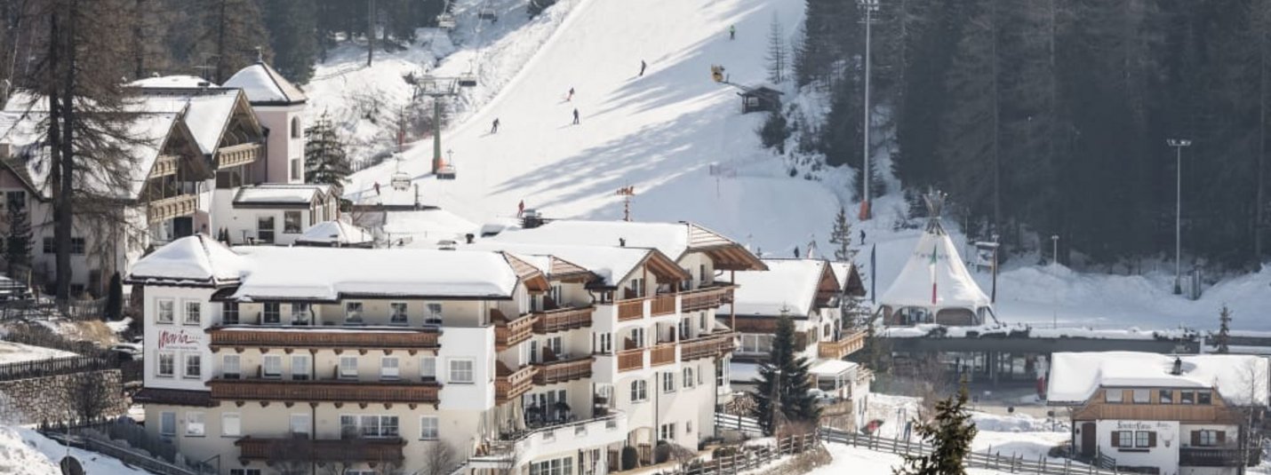 Sneeuwbedekt bergdorp met skiërs en stoeltjeslift in de winter
