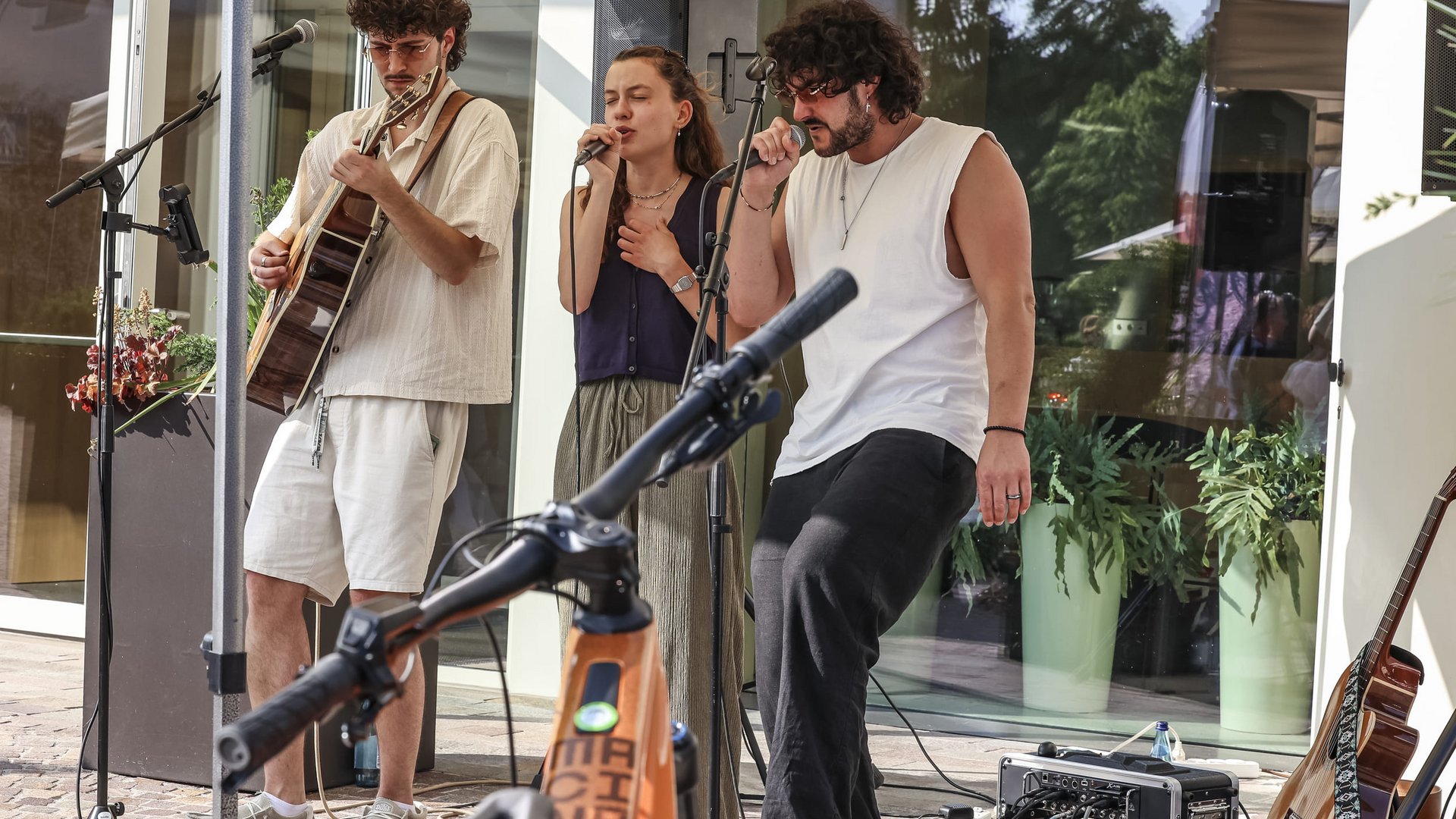 Drei Musiker führen im Freien mit Gitarre und Gesang auf