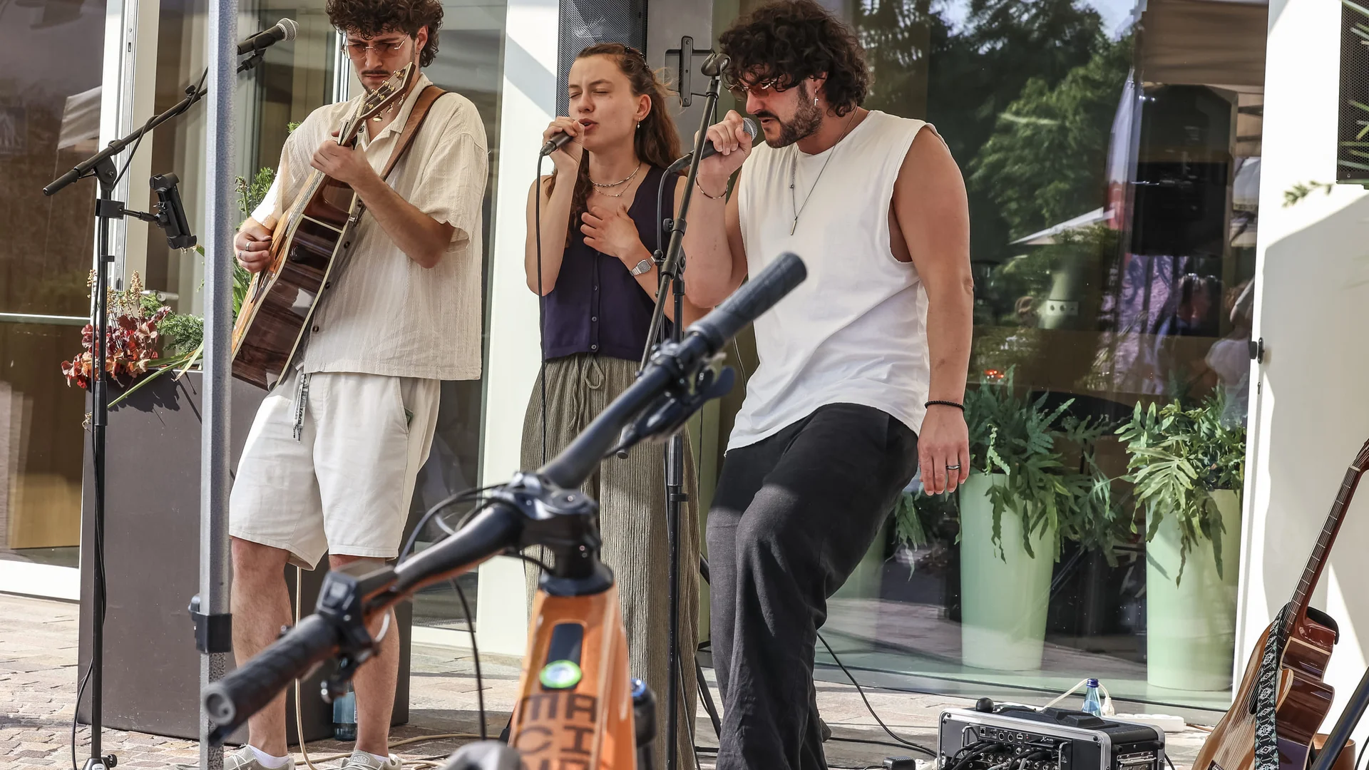 Genuss-(E-)Biken in den Dolomiten © Jens Vögele - Westsiders Drei Musiker führen im Freien mit Gitarre und Gesang auf
