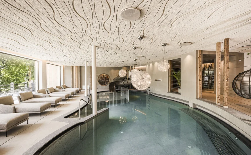 Indoor pool with lounge chairs and modern lighting in a relaxing setting