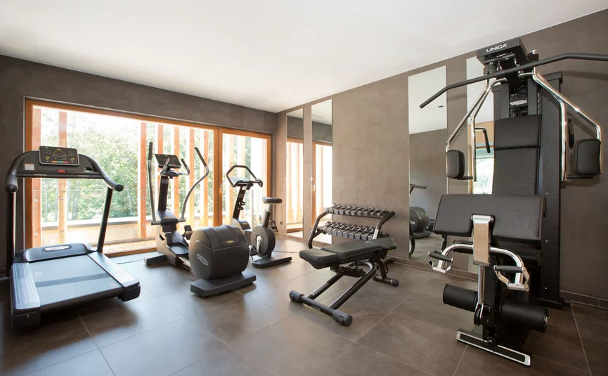 Hell beleuchteter Fitnessraum mit Laufband, Hanteln und Trainingsgeräten