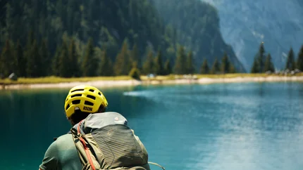 Mountainbiker mit gelbem Helm an einem Bergsee