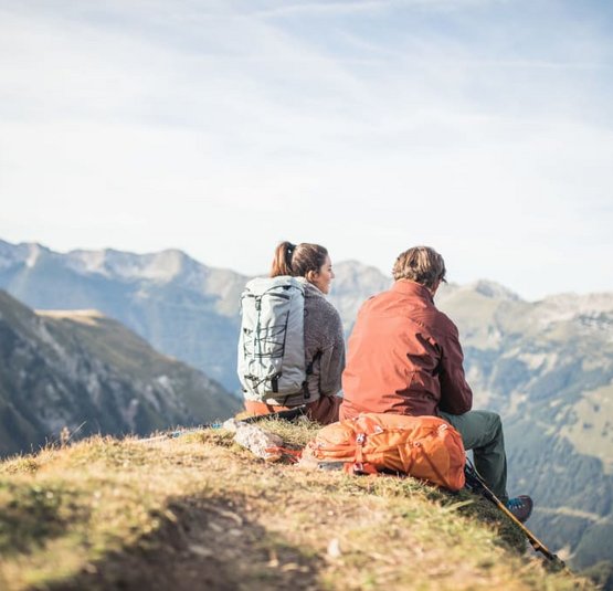 5=4 Tage Zugspitze Bergfrühling Zwei Wanderer sitzen mit Rucksäcken und schauen auf Bergpanorama