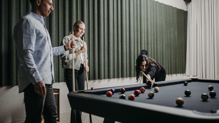 MTB in der DNA: Bikesommer im DIPS&DROPS © Matthias Warter Drei Personen spielen Billard in einem modernen Raum