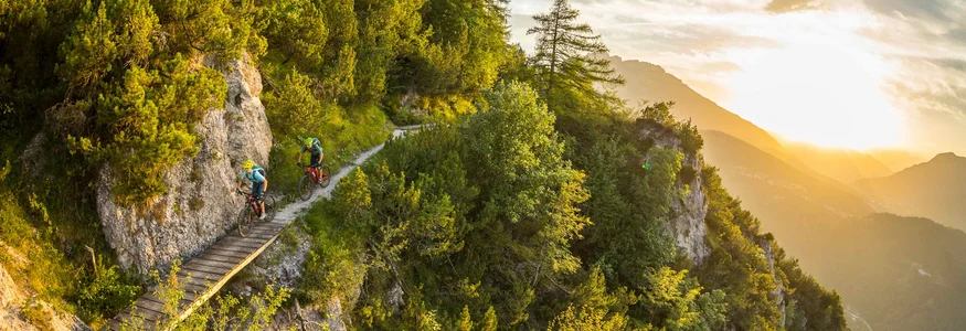 Levico Lake © WOM Medien - Andreas Meyer Two mountain bikers on narrow mountain trail at sunset