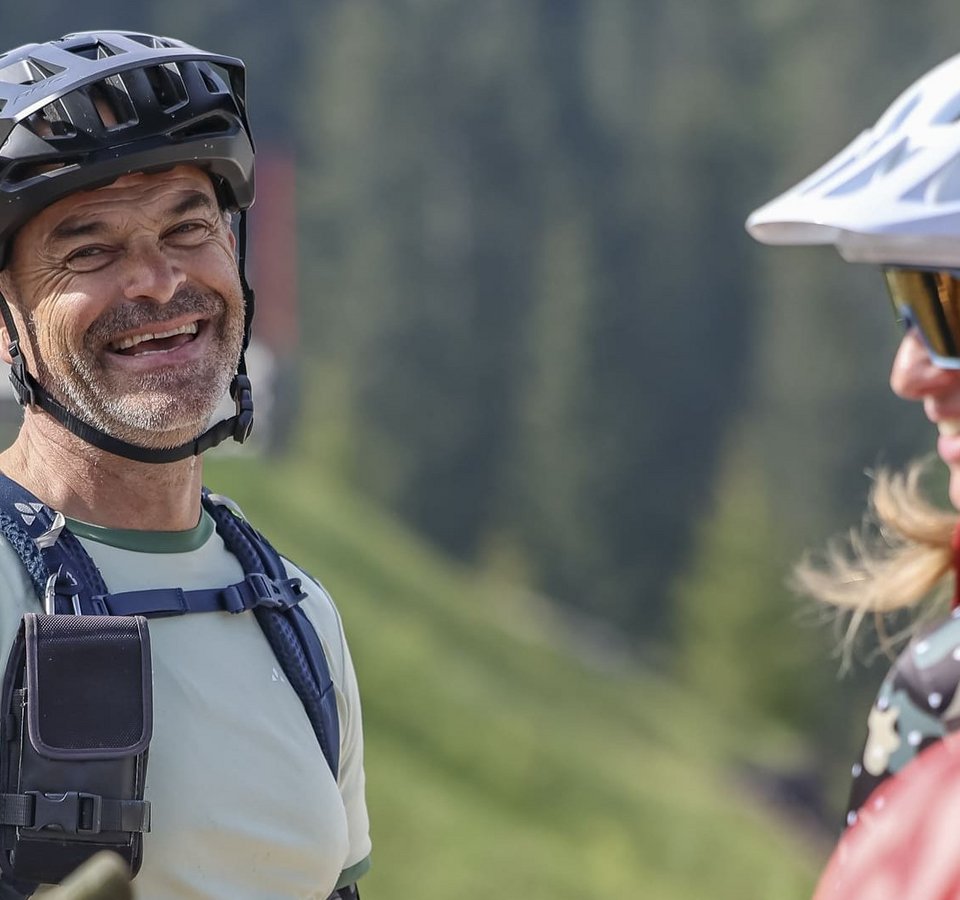 Gruppe fröhlicher Mountainbiker in Helm und Schutzkleidung im Grünen