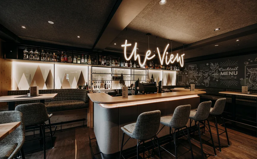 Modern bar with illuminated counter and shelves stocked with spirits