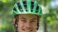 Junger Mann mit grünem Helm und orangefarbenem T-Shirt im Freien