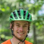 Junger Mann mit grünem Helm und orangefarbenem T-Shirt im Freien