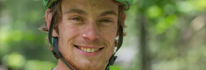 Junger Mann mit grünem Helm und orangefarbenem T-Shirt im Freien