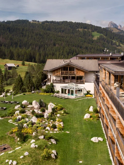 Hotel mit Pool auf Balkon und grüner Berglandschaft im Hintergrund