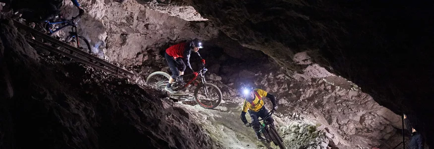 Mountainbiker fahren bei Nacht in einem beleuchteten Höhlentunnel