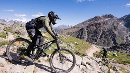 Mountainbiker fahren auf felsigem Bergweg bei klarem Himmel