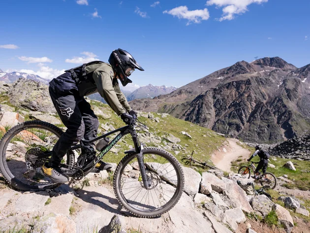 Mountainbiker fahren auf felsigem Bergweg bei klarem Himmel
