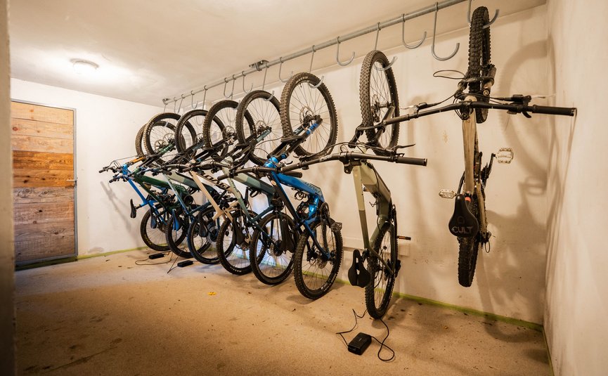 Seven bicycle tires hanging on hooks in a bike storage room