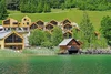 Holzferienhäuser am See mit grünen Bäumen und Hügeln im Hintergrund