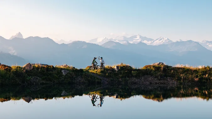 Mountain Bike Holidays © Mathäus Gartner Zwei Mountainbiker feiern mit Bergblick am Seeufer