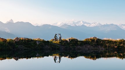 Twee mountainbikers vieren met bergzicht aan het meer