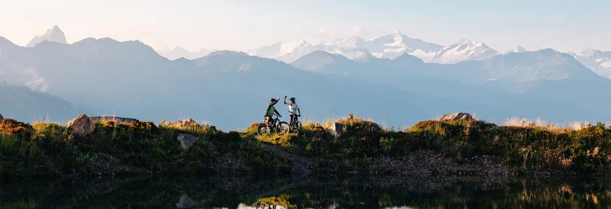 Welcher Hohe Salve-MTB-Typ bist du? © Mathäus Gartner Zwei Mountainbiker feiern mit Bergblick am Seeufer