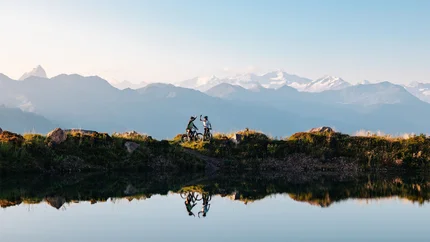 Twee mountainbikers vieren met bergzicht aan het meer
