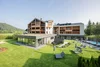 Modernes Hotel mit Liegestühlen im Garten und Bergen im Hintergrund