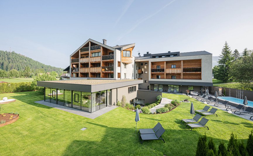 Modern hotel with lounge chairs on grass and mountains in background