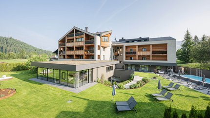 Modernes Hotel mit Liegestühlen im Garten und Bergen im Hintergrund