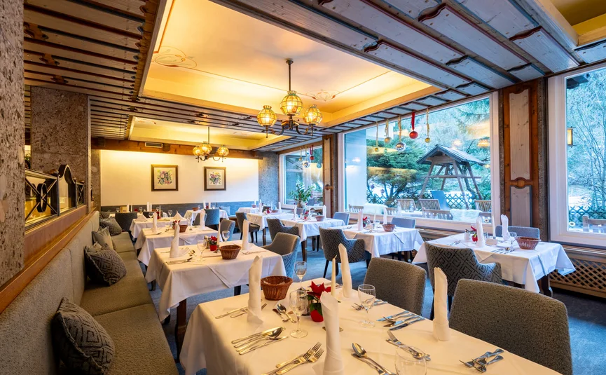 Weihnachtlich dekoriertes Restaurant mit gedeckten Tischen und Winterblick