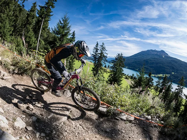 GREEN DAYS 2026 in Nauders-Reschensee
© Manfred Stromberg Mountainbiker fährt auf felsigem Waldweg mit Berg und See im Hintergrund