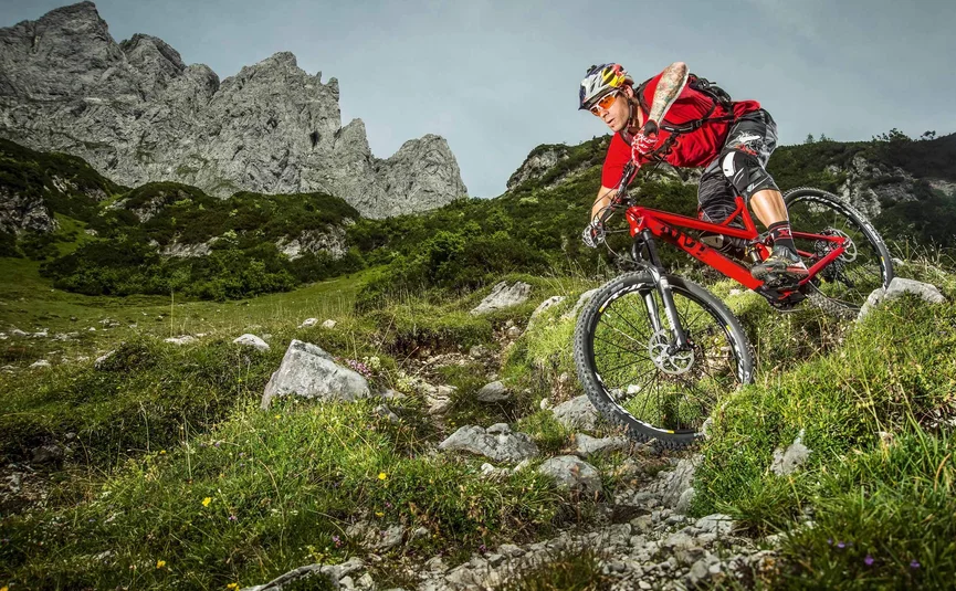 Mountainbiker fährt Trails in bergiger Landschaft mit Felsen und grüner Vegetation