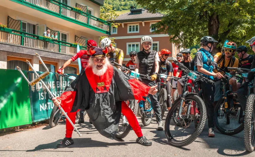 Group of cyclists wearing helmets and a man in a red devil costume