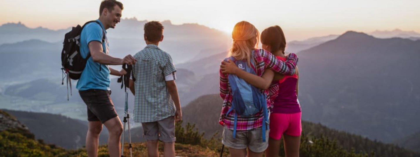 Family hiking on a mountain enjoying sunset view