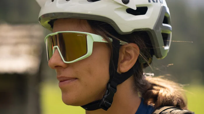Frau mit Fahrradhelm und Sonnenbrille in Berglandschaft