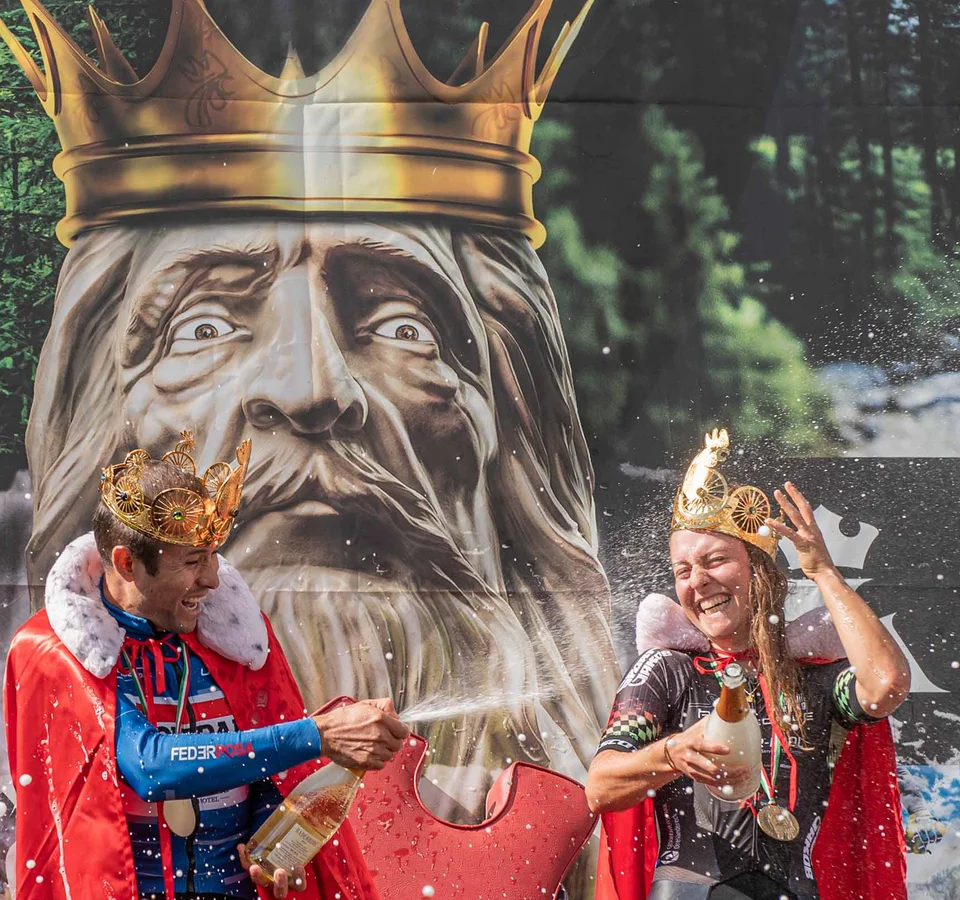 Kronplatz King Marathon – The King of the Dolomites Zwei Radfahrer feiern mit Kronen und Umhängen nach MTB-Marathon-Sieg