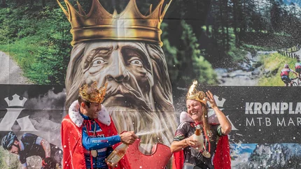 Zwei Radfahrer feiern mit Kronen und Umhängen nach MTB-Marathon-Sieg