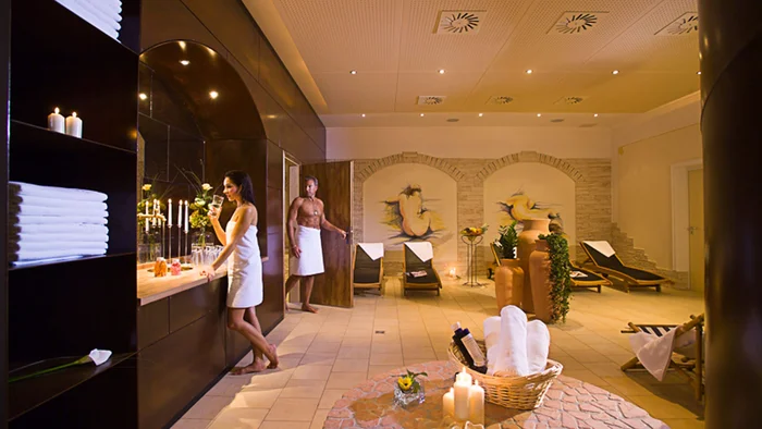 Relaxing spa room with loungers, candles, and people in towels