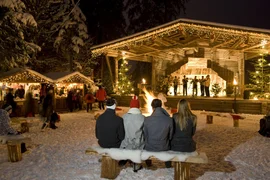 Winterse kerstmarkt met verlicht podium en publiek bij een kampvuur