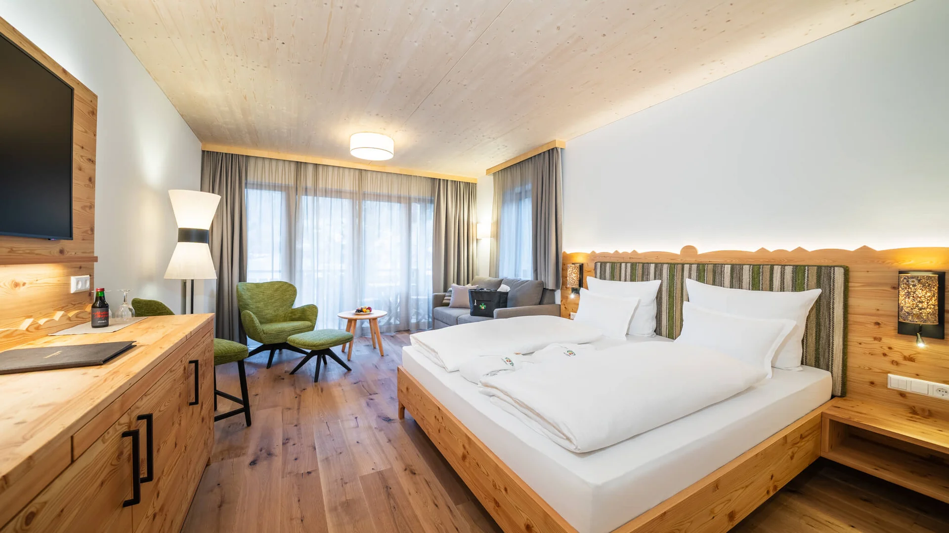Modernes Hotelzimmer mit Holzmöbeln und großen Fenstern mit Gardinen