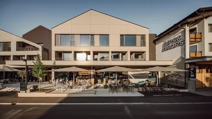 Außenansicht von Dips & Drops Bistro mit Terrasse und Gästen bei Sonnenlicht