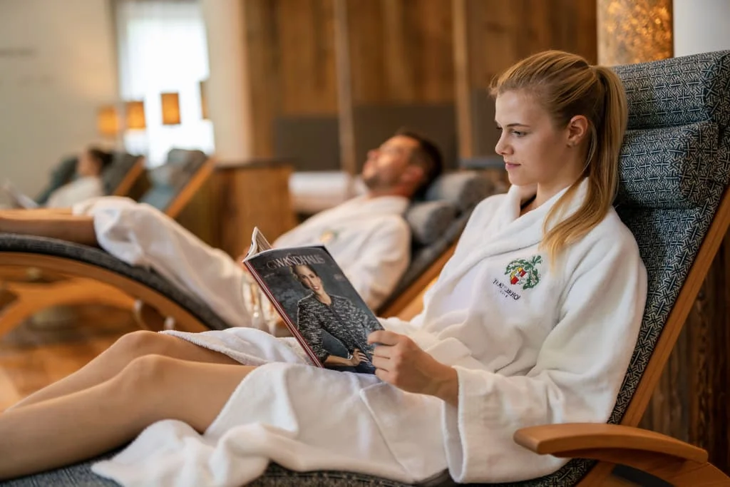Midweek im Dezember Frau im Bademantel liest in einem Liegestuhl ein Magazin