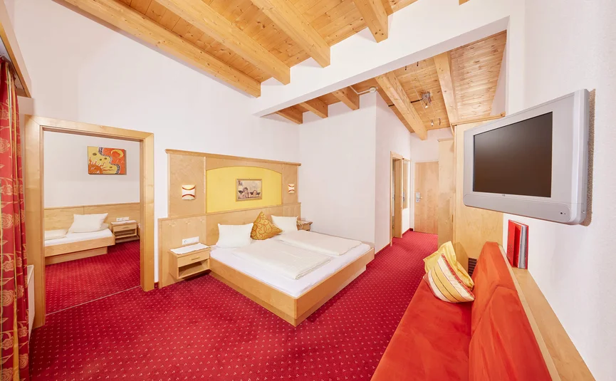 Hotel room with red carpet, wooden furniture, and exposed beams