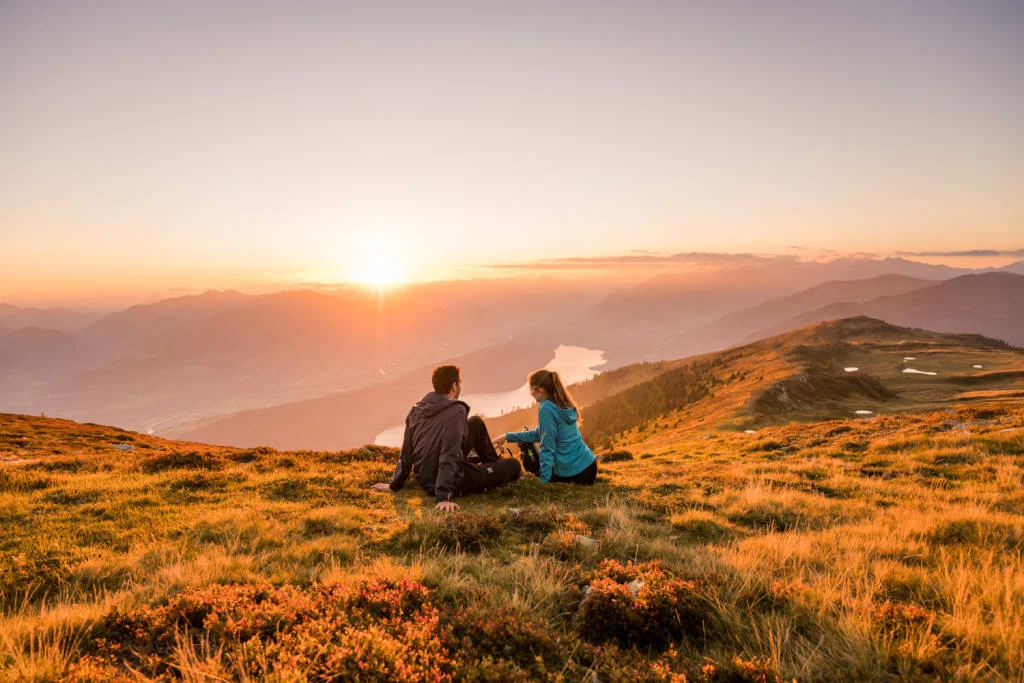 Herbstgefühl für Zwei Stel zit op grasheuvel kijkt naar zonsondergang over vallei en meer