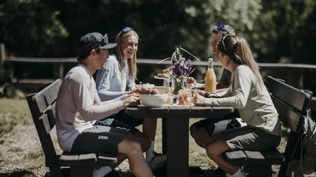 Was steckt hinter dem Umweltengagement von Bikehotels? Vier junge Menschen sitzen draußen am Tisch und essen gemeinsam