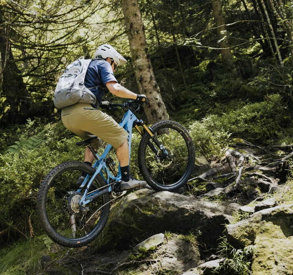 #Uphillflow – der Spaß beginnt schon bergauf © Bosch eBike Systems Mountainbiker mit Helm und Rucksack fährt über einen felsigen Waldweg