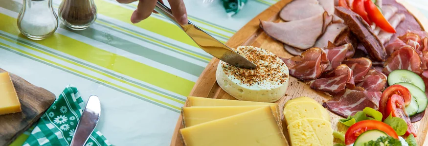 Best of Bregenzerwald © David Karg Messer schneidet Käse auf einer Platte mit verschiedenen Käsesorten und Wurst