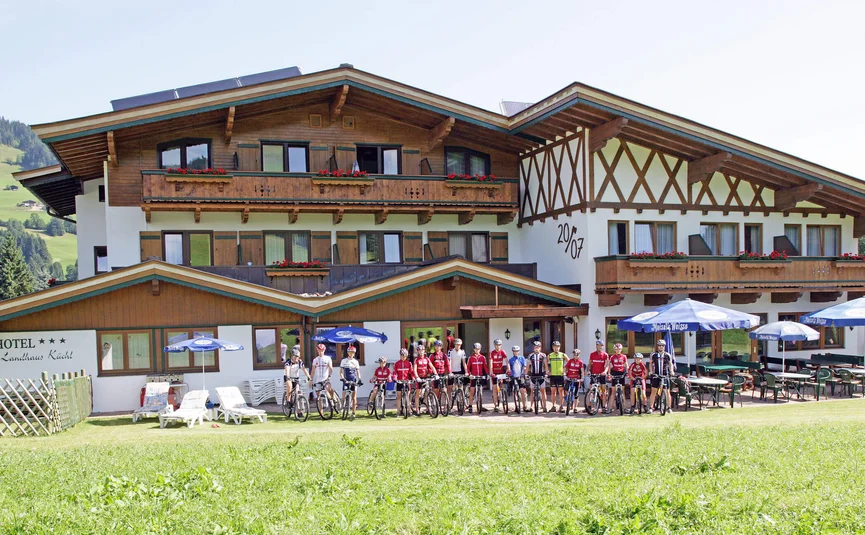 Gruppe von Radfahrern vor einem traditionellen Hotel in den Bergen