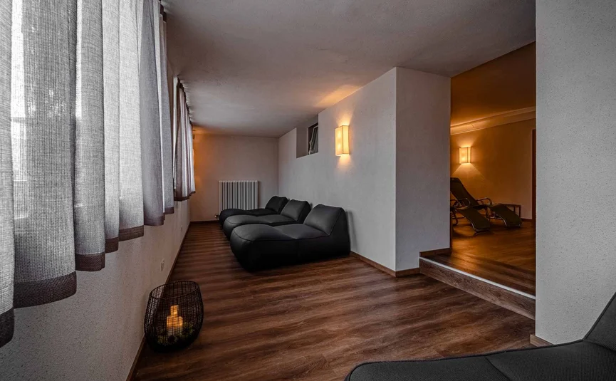Relaxation room with black lounge chairs, wooden floor, and soft lighting