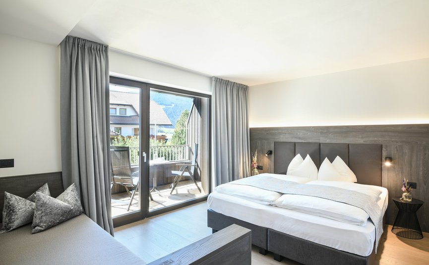 Alpinhotel Keil **** © Harald Wisthaler Bright modern hotel room with large bed and balcony overlooking houses and mountains