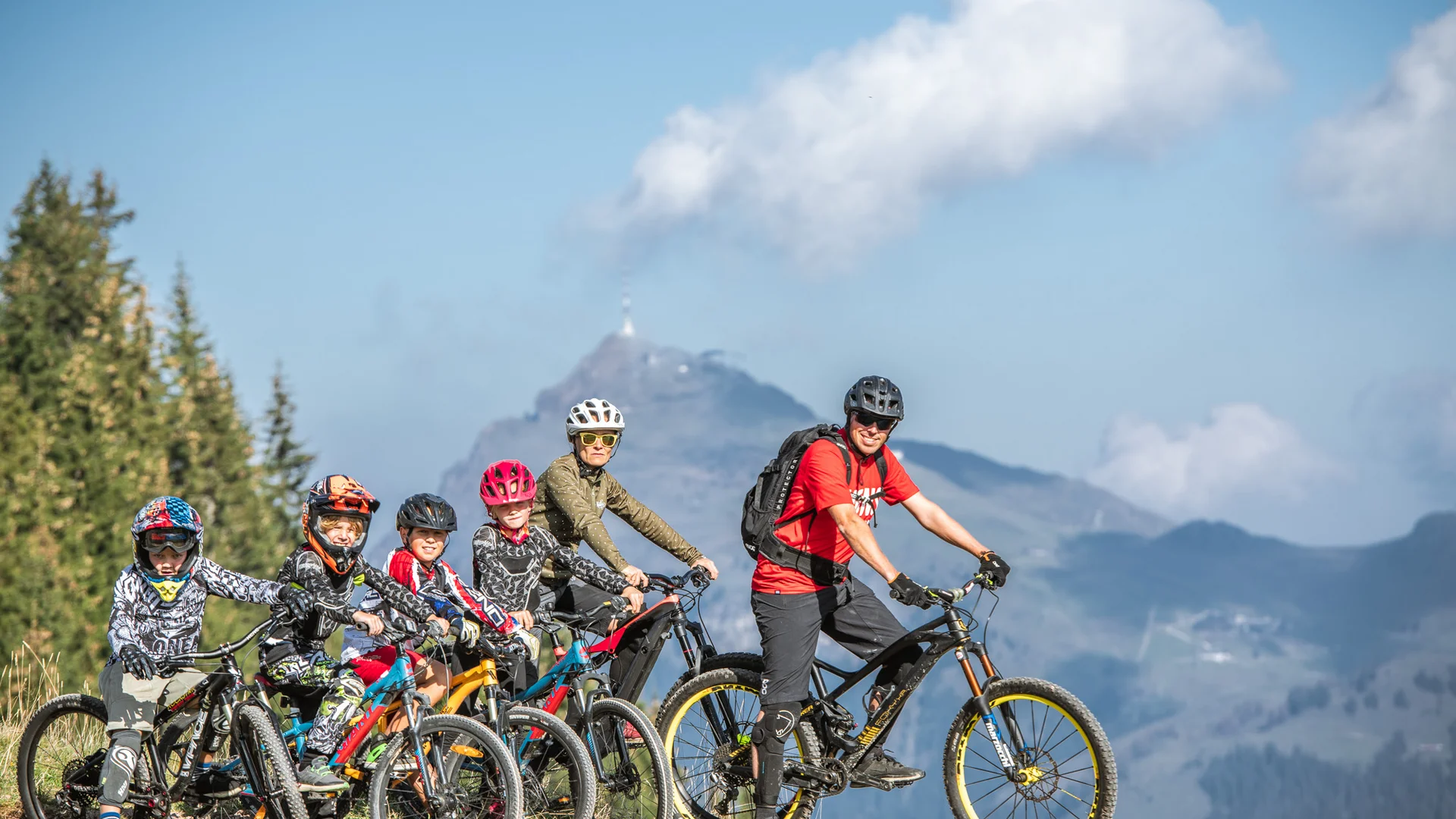 Gruppe von Radfahrern mit Helmen auf Bergpfad vor Bergkulisse