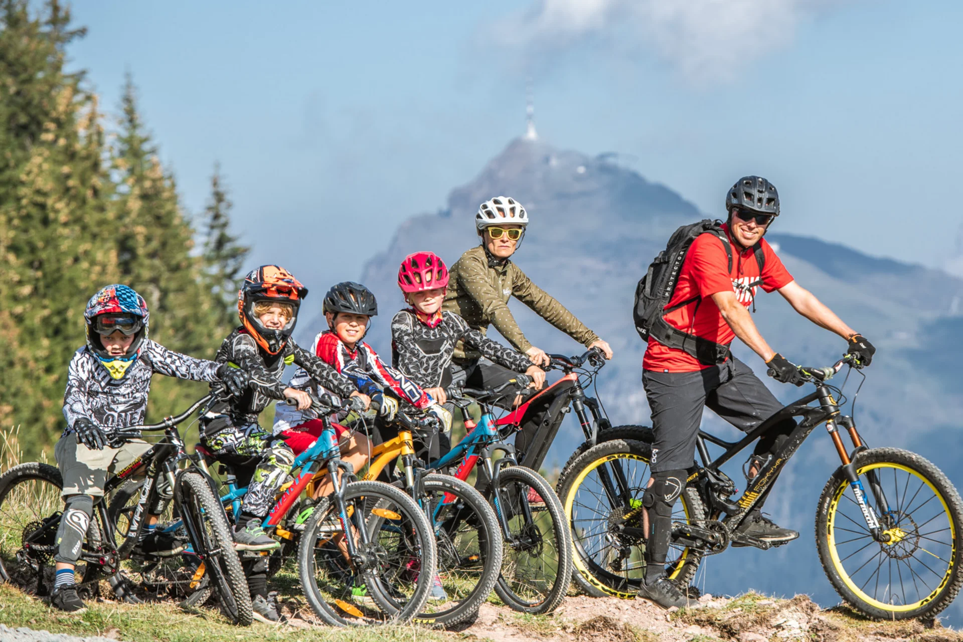 Gruppe von Radfahrern mit Helmen auf Bergpfad vor Bergkulisse